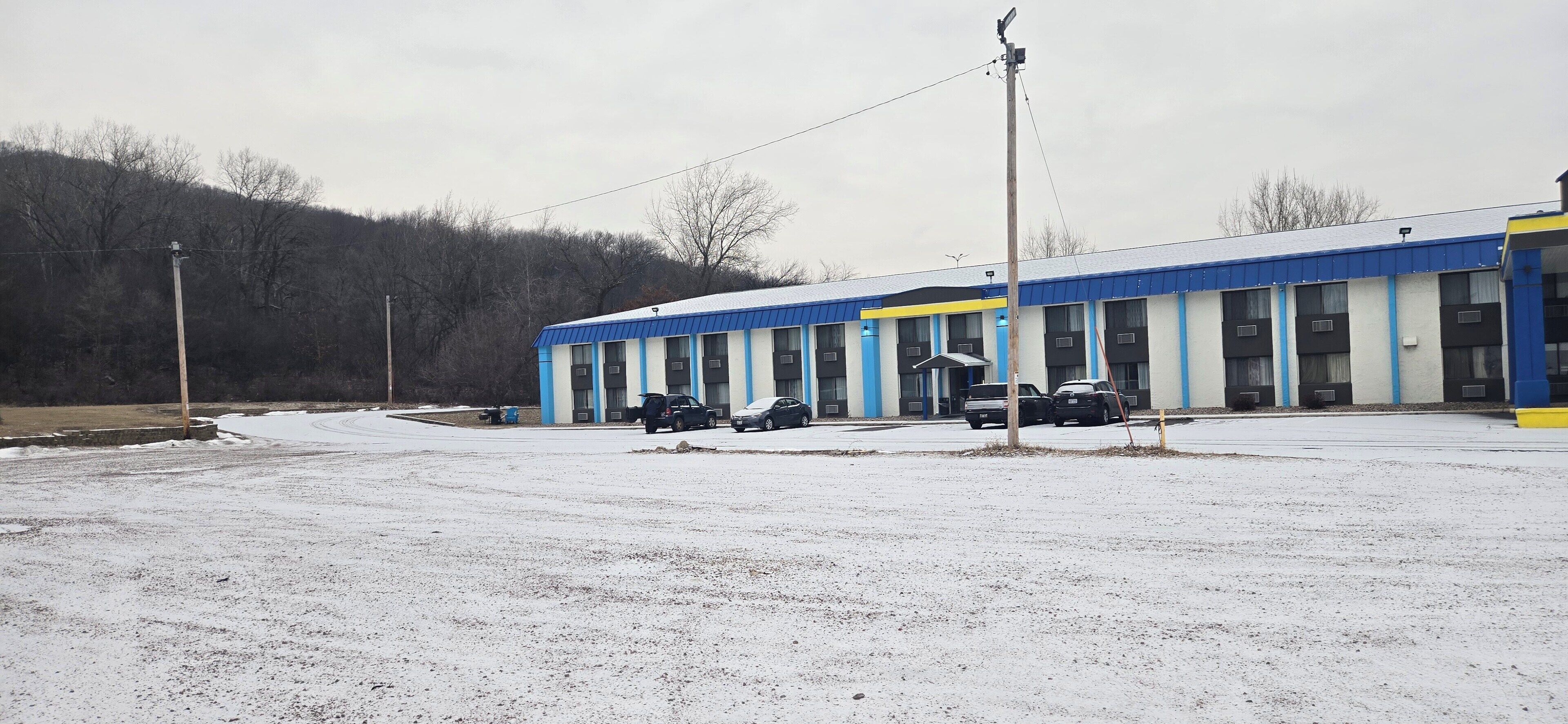 Un edificio con fachada azul y blanca, varios espacios de estacionamiento y suelo cubierto de nieve.