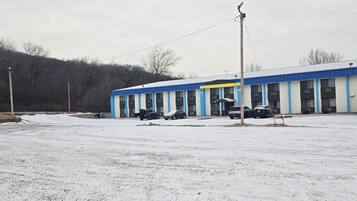 Un edificio con fachada azul y blanca, varios espacios de estacionamiento y suelo cubierto de nieve.