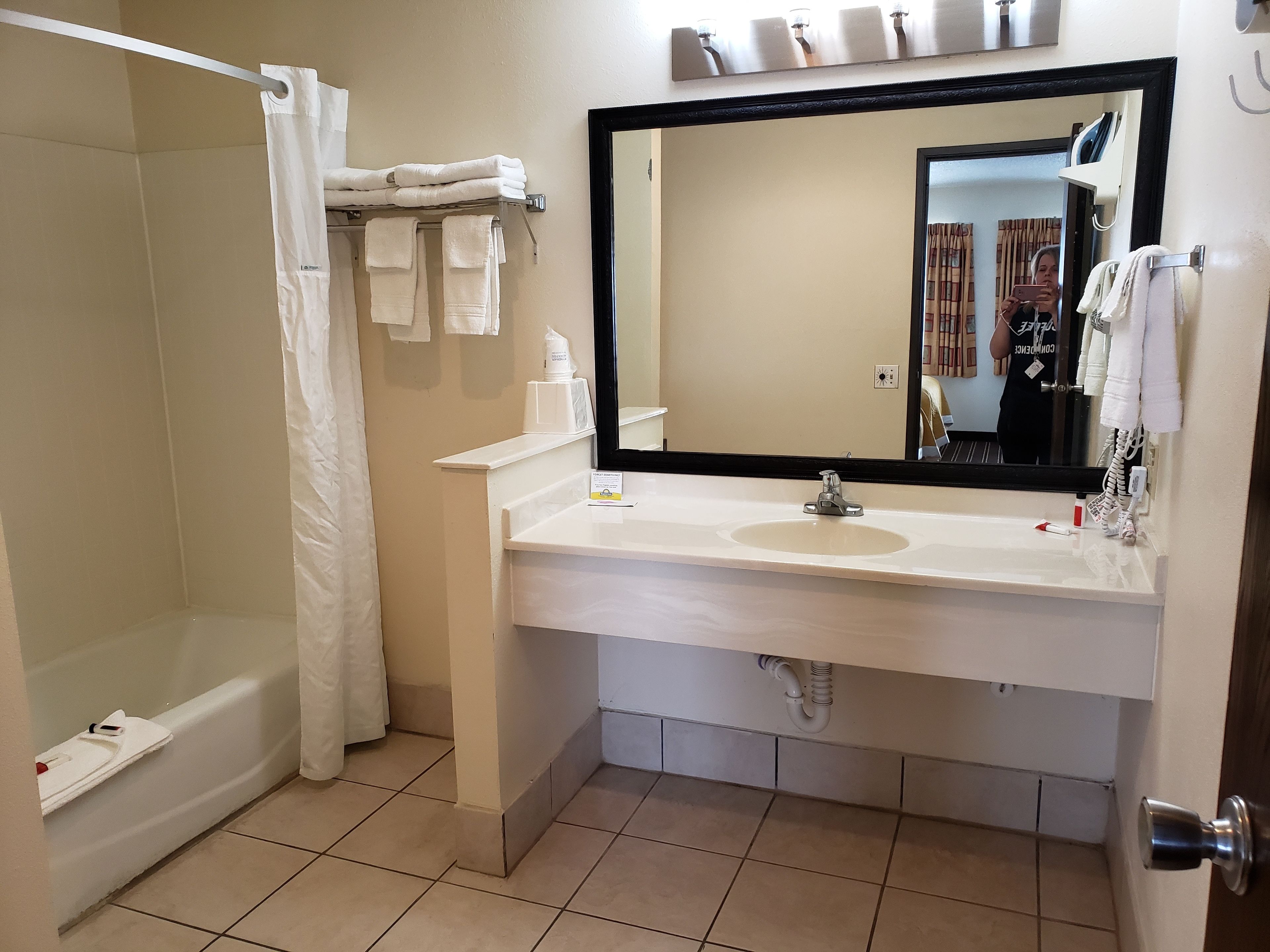 A bathroom with a bathtub, a sink, a mirror, and towels.