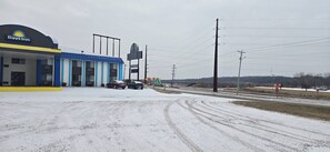 A Days Inn with a blue and yellow facade, a gas station, and a highway with road signs.