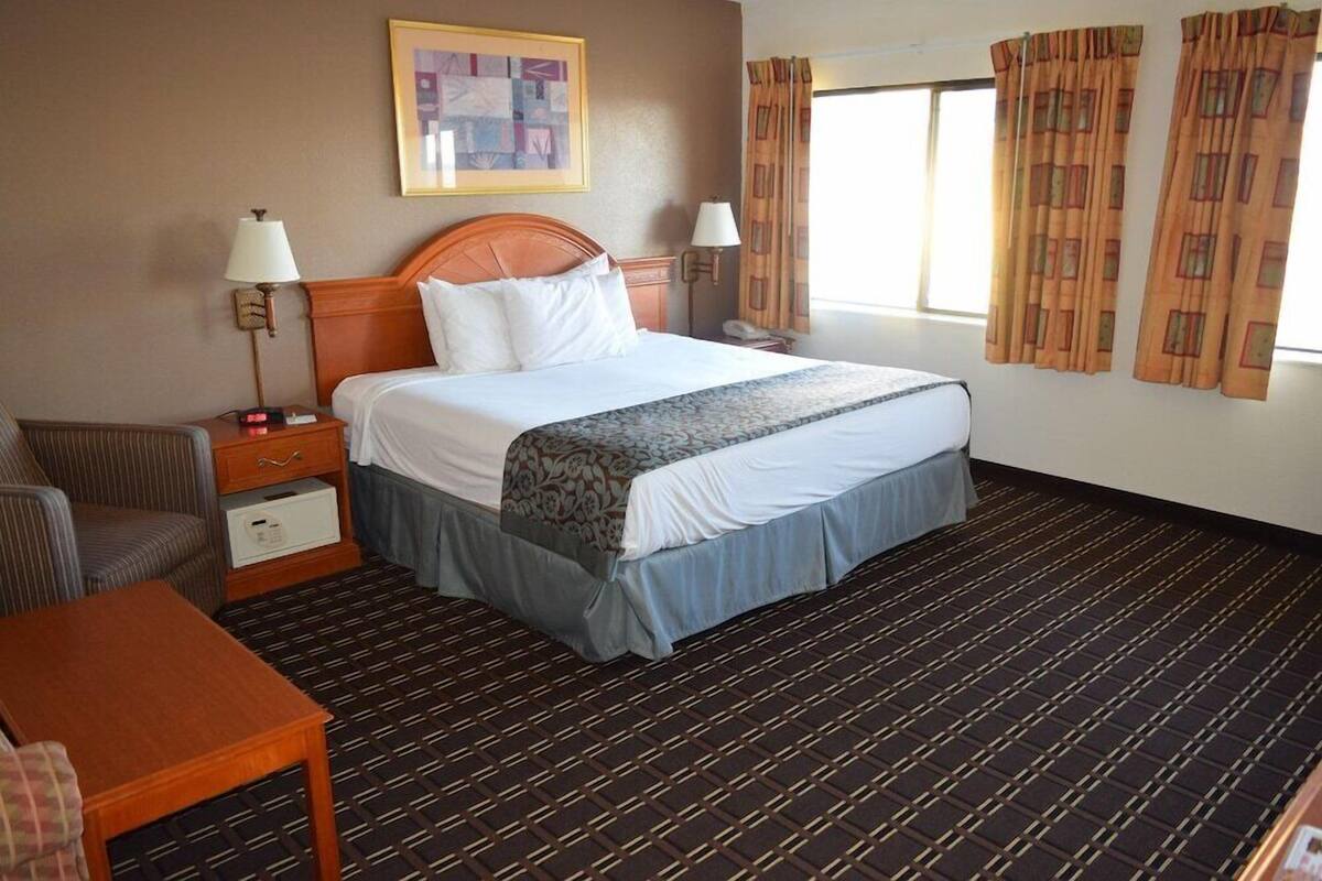 A hotel room with a large bed, two bedside tables, a chair, and a small table.