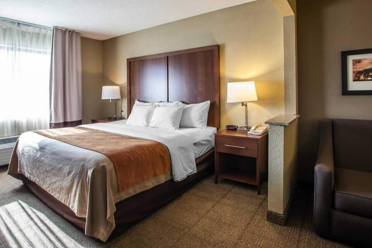 A hotel room with a large bed, two bedside tables, a chair, and a framed picture on the wall.