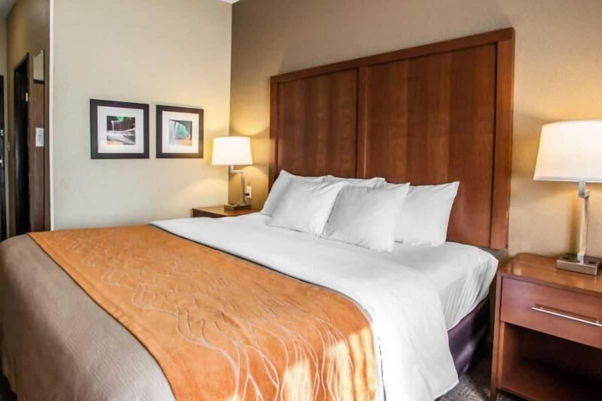 A hotel room with a large bed, two bedside tables with lamps, and framed pictures on the wall.