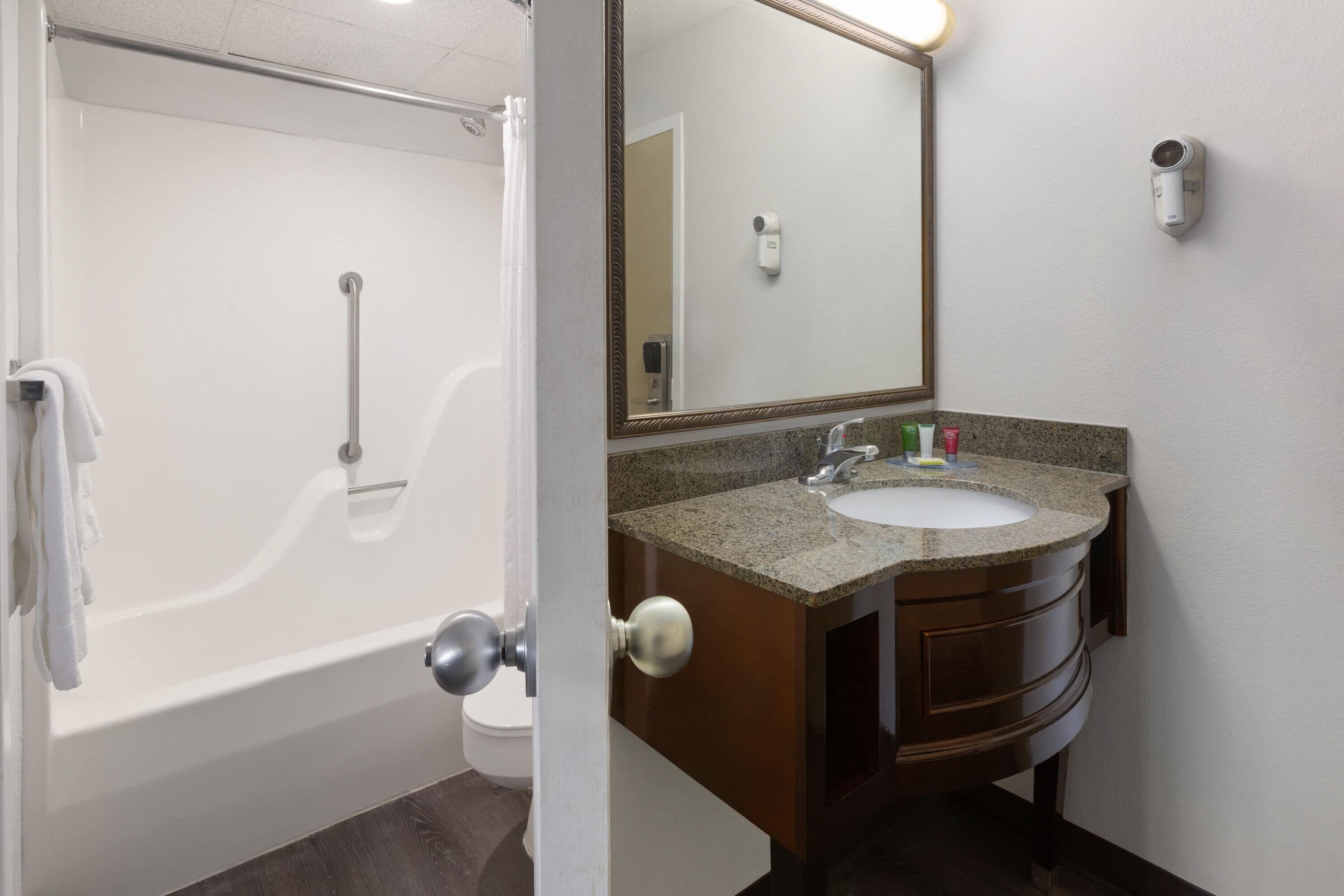 Une salle de bain avec une baignoire, un lavabo, un miroir et un porte-serviettes.