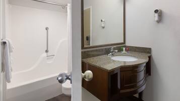 Une salle de bain avec une baignoire, un lavabo, un miroir et un porte-serviettes.