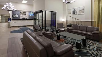 A hotel lobby with leather seating, a reception desk, and a chandelier.