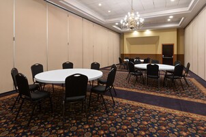 A conference room with round tables and chairs, a patterned carpet, and a chandelier.