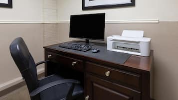 A dark wood desk with a black monitor, a keyboard, a mouse, and a Canon printer.