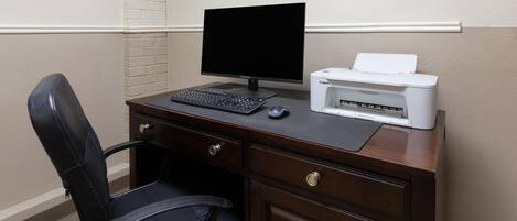 A dark wood desk with a black monitor, a keyboard, a mouse, and a Canon printer.