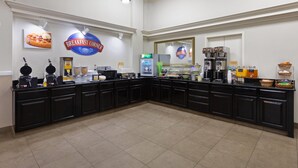 A breakfast corner with a waffle maker, coffee machines, and a sign for breakfast. - Baymont by Wyndham Festus (Festus)