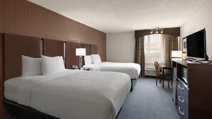 A hotel room with two beds, a desk with a TV, a chair, and a window with curtains. - Baymont by Wyndham Festus (Festus)