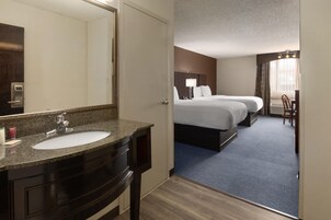 Una habitación de hotel con baño, cama, escritorio y silla.
