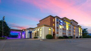 Ein mehrstöckiges Hotel mit Ziegelverkleidung und großen Fenstern, vor dem sich ein Parkplatz befindet.