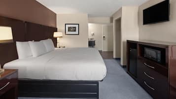 Una habitación de hotel con una cama grande, un escritorio con lámpara, televisión y un baño a la vista.