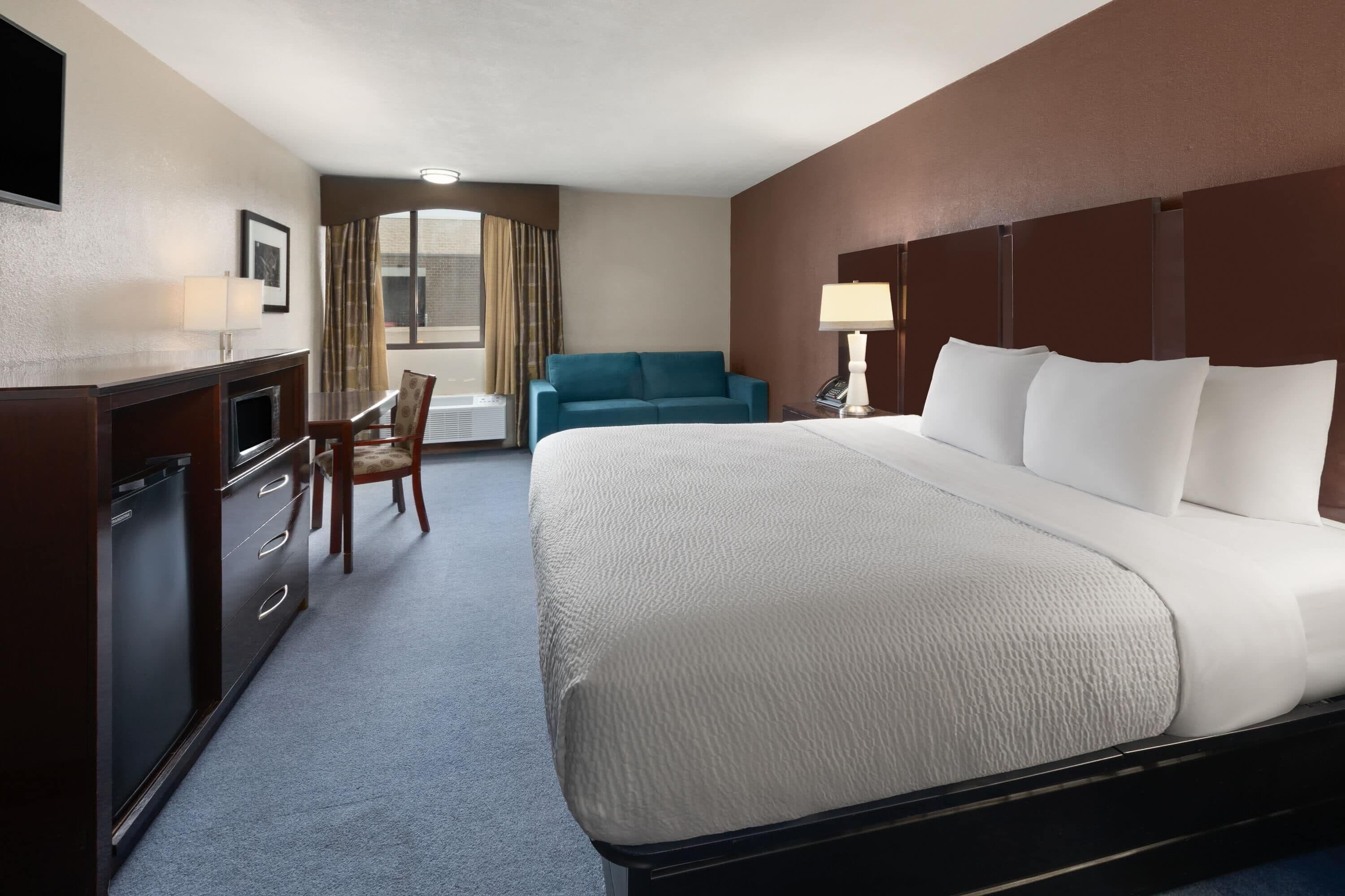 Habitación de hotel con una cama grande, un escritorio, una silla, un sofá y una lámpara.