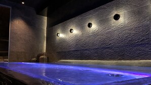 A spa area with a heated floor, a wall with circular lights, and a water feature.
