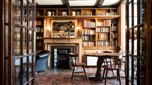 A library with bookshelves, a fireplace, and a table with chairs.