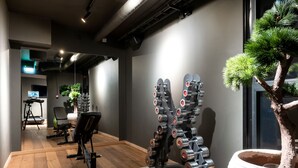 A gym with exercise equipment, a treadmill, and a potted tree.