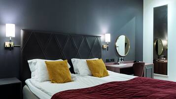 Una habitación de hotel con una cama grande, dos lámparas de noche, un escritorio y un espejo.