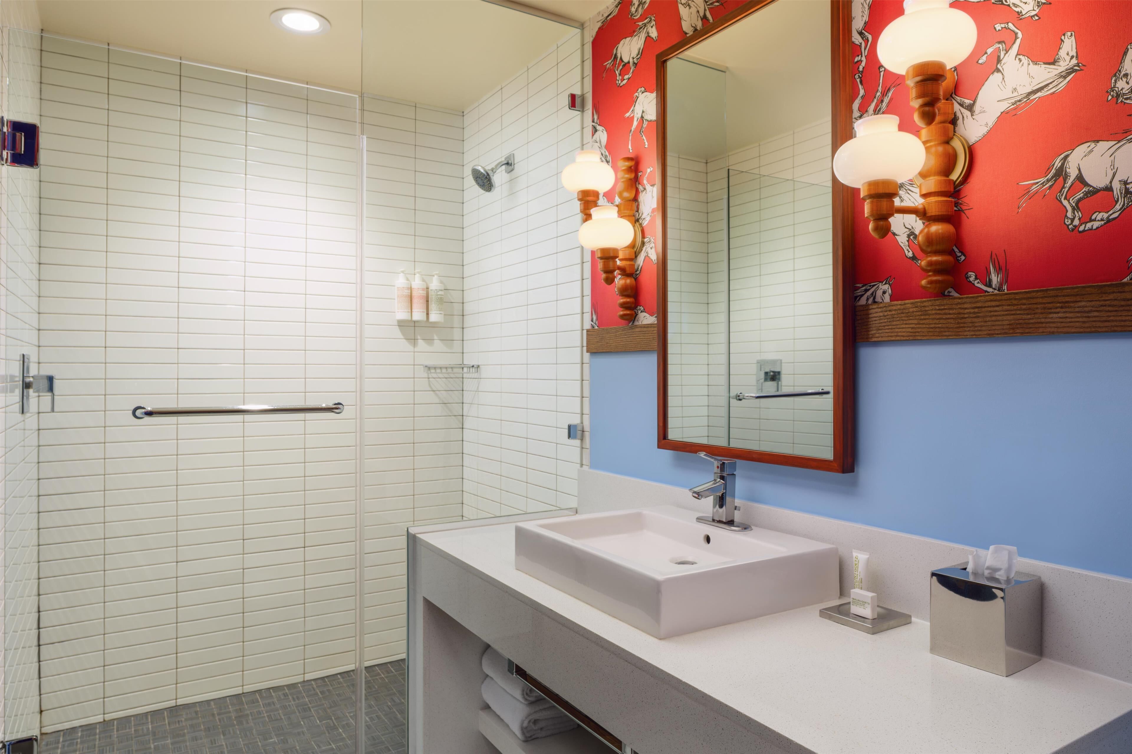 A modern bathroom with a shower, a sink, and a mirror.
