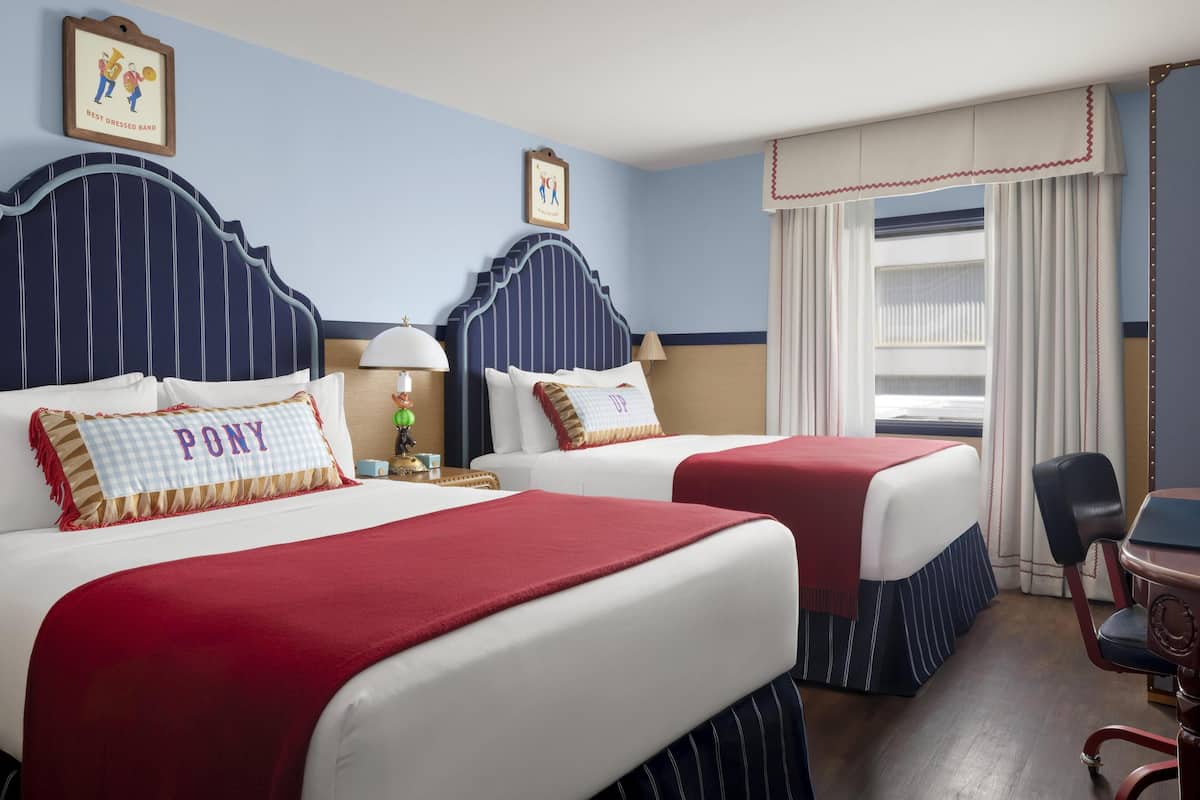 A hotel room with two beds, each with a red and white bedspread, and a framed picture on the wall.