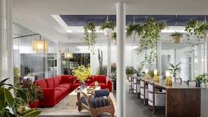 A modern living room with a red sofa, a coffee table, and hanging plants. - Graduate by Hilton Dallas (Dallas)