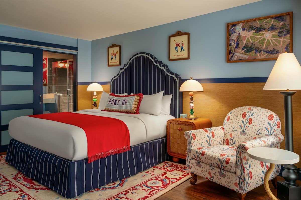 A hotel room with a large bed, two bedside tables, a chair, and a small table.
