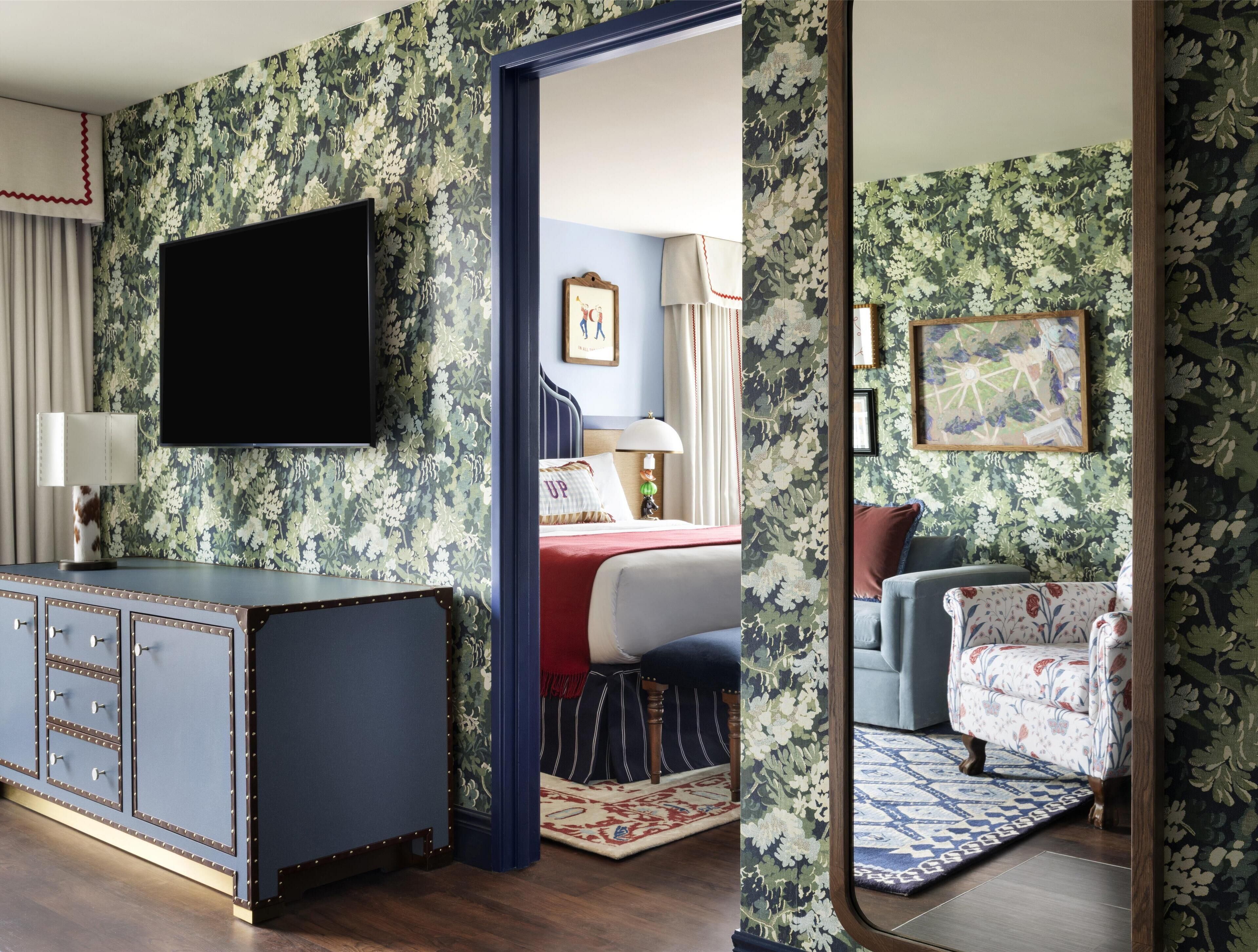 A room with a bed, a TV, a desk, and a mirror.
