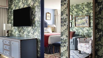 A room with a bed, a TV, a desk, and a mirror.