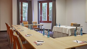 Un salón de conferencias con una larga mesa, sillas y un proyector.