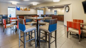 A restaurant with high tables and booths, a kitchen area, and a clock on the wall. - Comfort Inn Grand Rapids Airport (Grand Rapids)