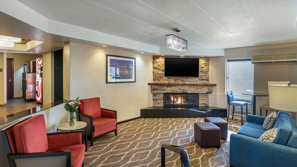 A hotel lobby with a fireplace, seating area, and a television mounted on the wall. - Comfort Inn Grand Rapids Airport (Grand Rapids)