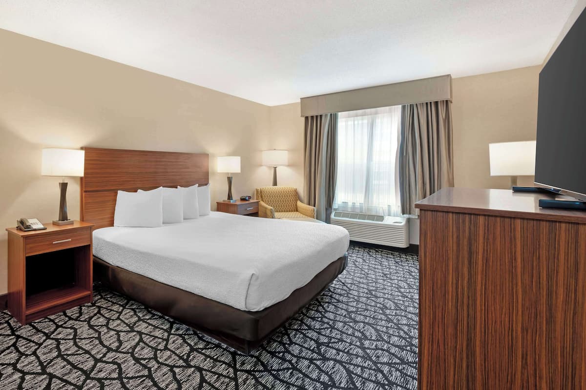 A hotel room with a large bed, two bedside tables with lamps, a desk, and a television.