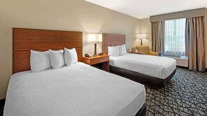 A hotel room with two beds, a desk, a chair, a lamp, and a window with curtains. - Best Western Westminster Hotel (Westminster)
