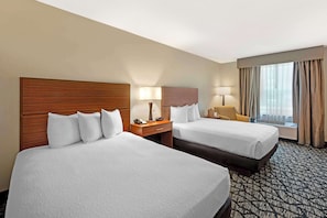 A hotel room with two beds, a desk, a chair, a lamp, and a window with curtains. - Best Western Westminster Hotel (Westminster)