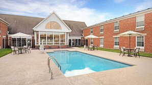 A swimming pool with lounge chairs and umbrellas, surrounded by brick buildings with large windows. - Best Western Westminster Hotel (Westminster)