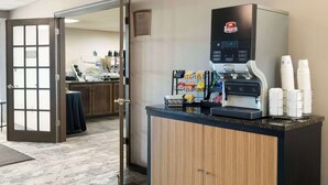 A coffee station with a Folgers coffee maker, disposable cups, and a variety of coffee pods. - Best Western Westminster Hotel (Westminster)