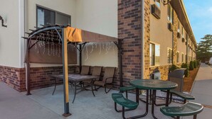 An outdoor patio area with a covered seating area, a table, and chairs.