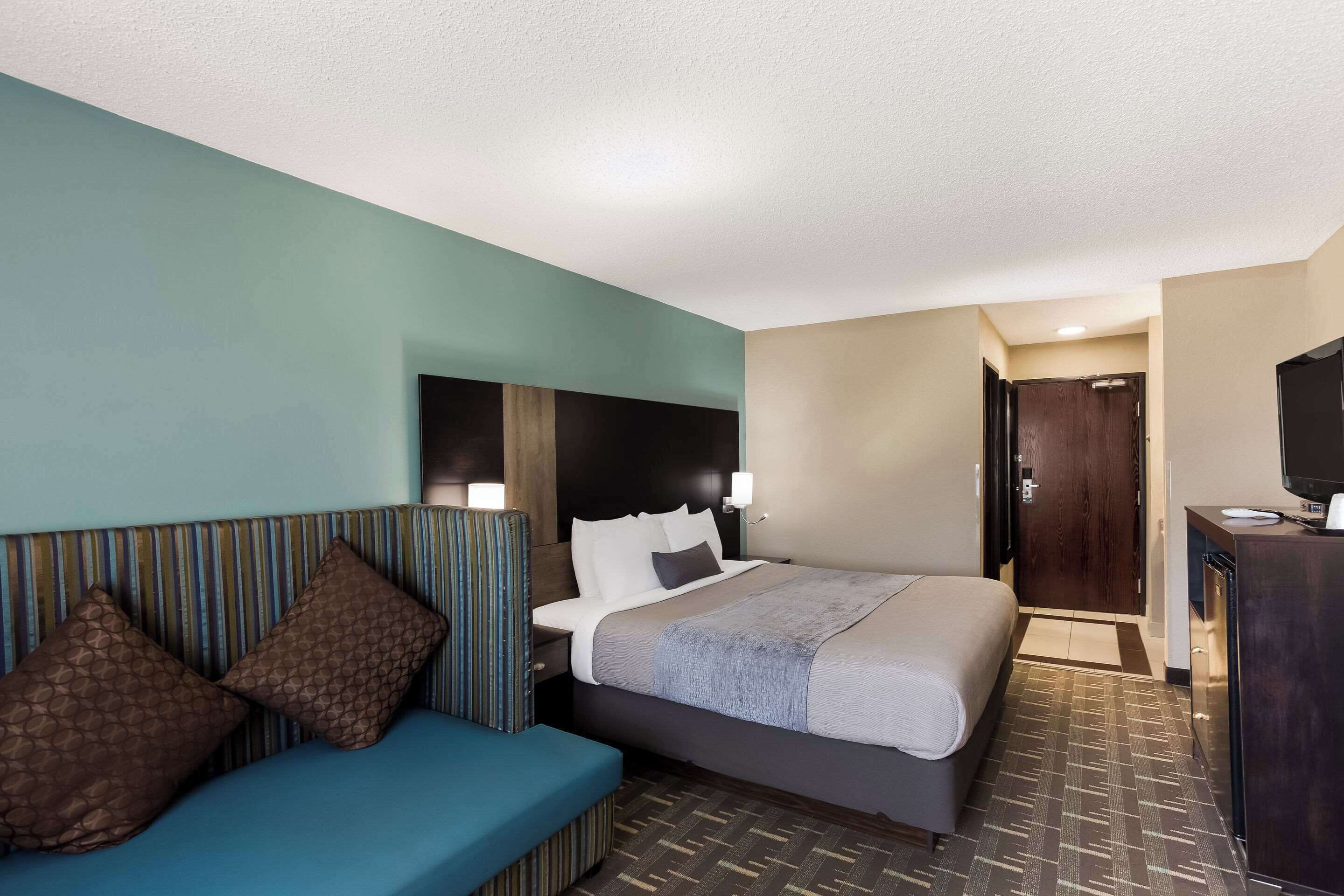 Ein Hotelzimmer mit Bett, Sofa, Schreibtisch und Fernseher.