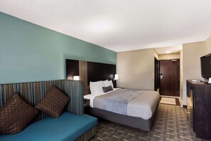 A hotel room with a bed, a sofa, a desk, and a television.