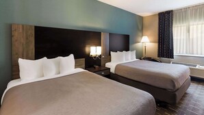A hotel room with two beds, a nightstand, a lamp, and a window with curtains.