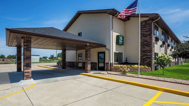 A hotel with a covered entrance, an American flag, and a sign indicating a quality rating.