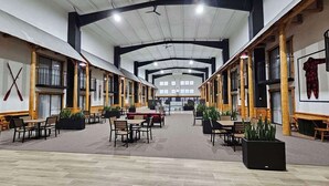 A spacious indoor area with multiple tables and chairs, wooden beams, and large windows. - Lumber Jack Lodge, an Ascend Collection Hotel (West Branch)