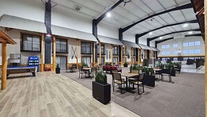 A spacious indoor area with multiple seating arrangements, including tables and chairs, and a coffee station. - Lumber Jack Lodge, an Ascend Collection Hotel (West Branch)