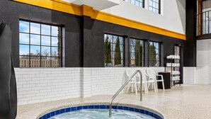 A modern indoor pool area with a hot tub, white tiled walls, and a yellow accent wall. - Lumber Jack Lodge, an Ascend Collection Hotel (West Branch)