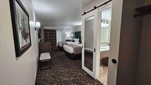 A hotel room with a bed, a desk, a chair, a mirror, and a framed picture on the wall. - Lumber Jack Lodge, an Ascend Collection Hotel (West Branch)