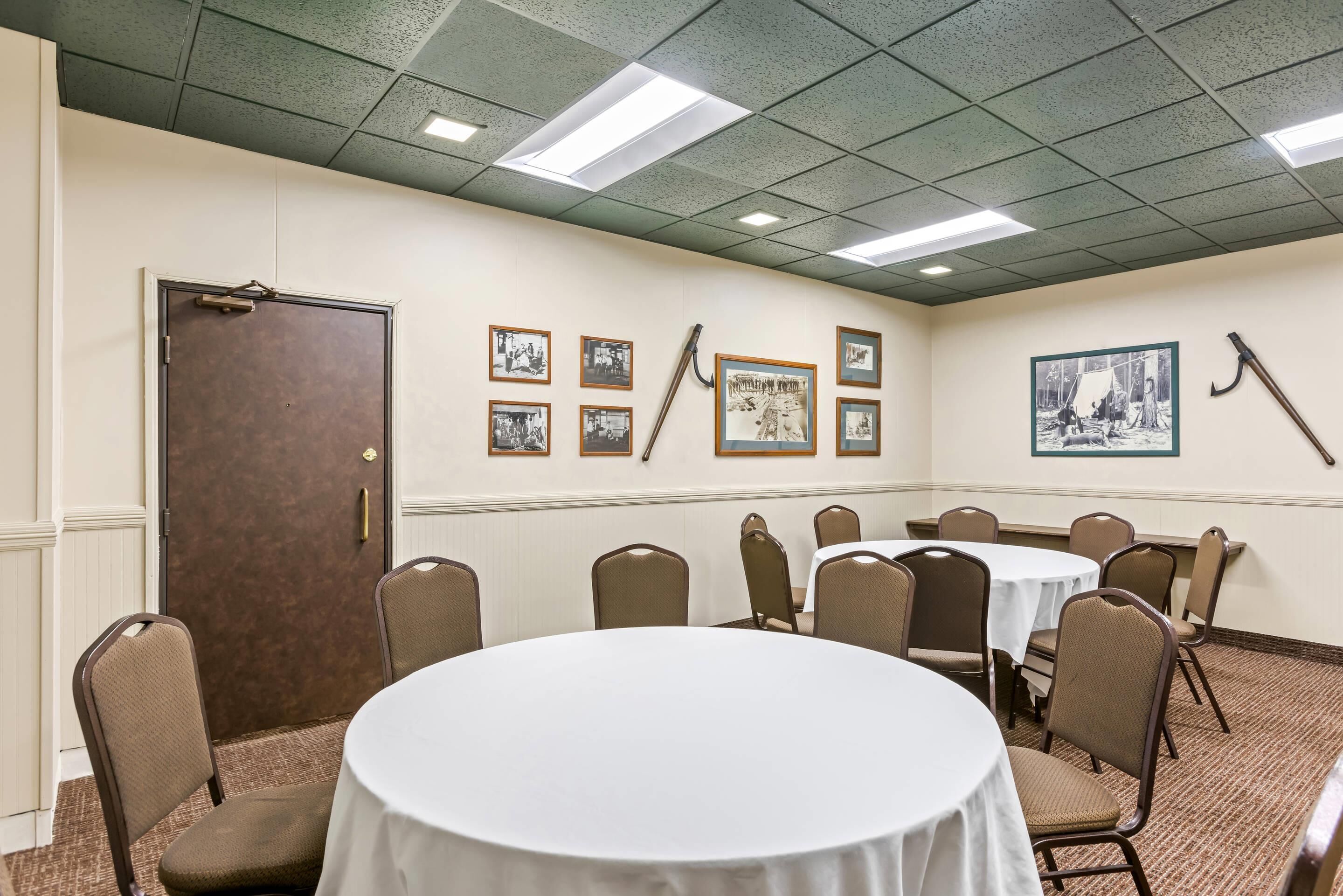 A conference room with a round table, chairs, and framed pictures on the wall.