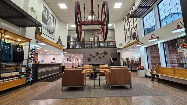 A spacious lobby with a high ceiling, a central seating area, and a staircase leading to an upper level. - Lumber Jack Lodge, an Ascend Collection Hotel (West Branch)