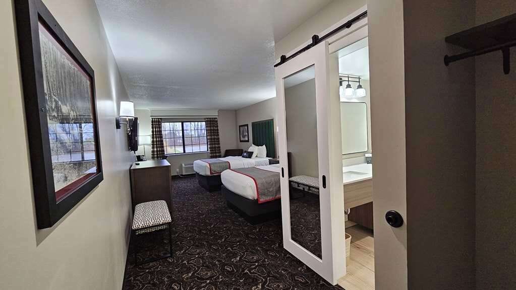 Hotelkamer met een bed, een bureau, een stoel, een tafeltje, een spiegel en een raam.