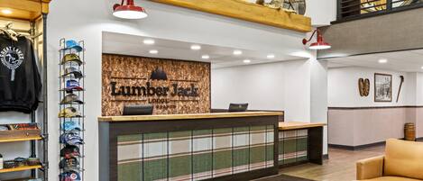 Un mostrador de recepción con un cartel que dice "Lumberjack Lodge" y una colección de sombreros en estantes a la izquierda.